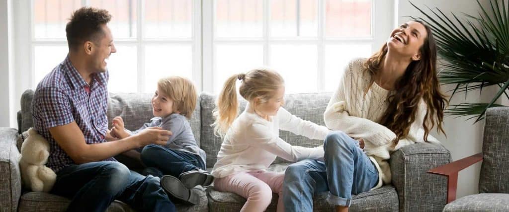Family relaxing together on the couch, smiling and having fun at home.
